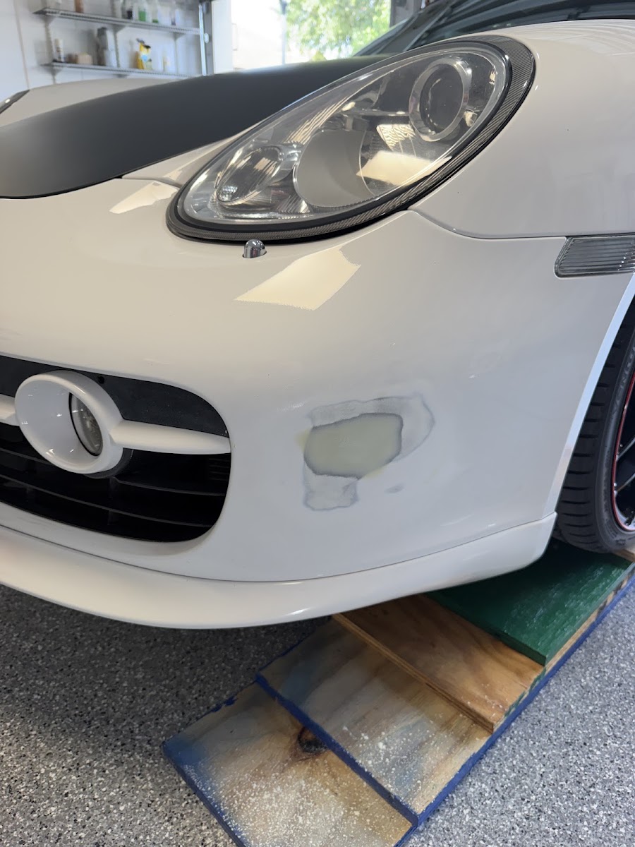 White Porsche bumper repair in progress in a garage
